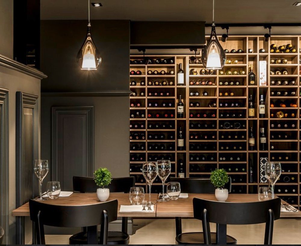 Sala del Ristorante Emporio a Rondissone con tavoli apparecchiati e parete cantina vini