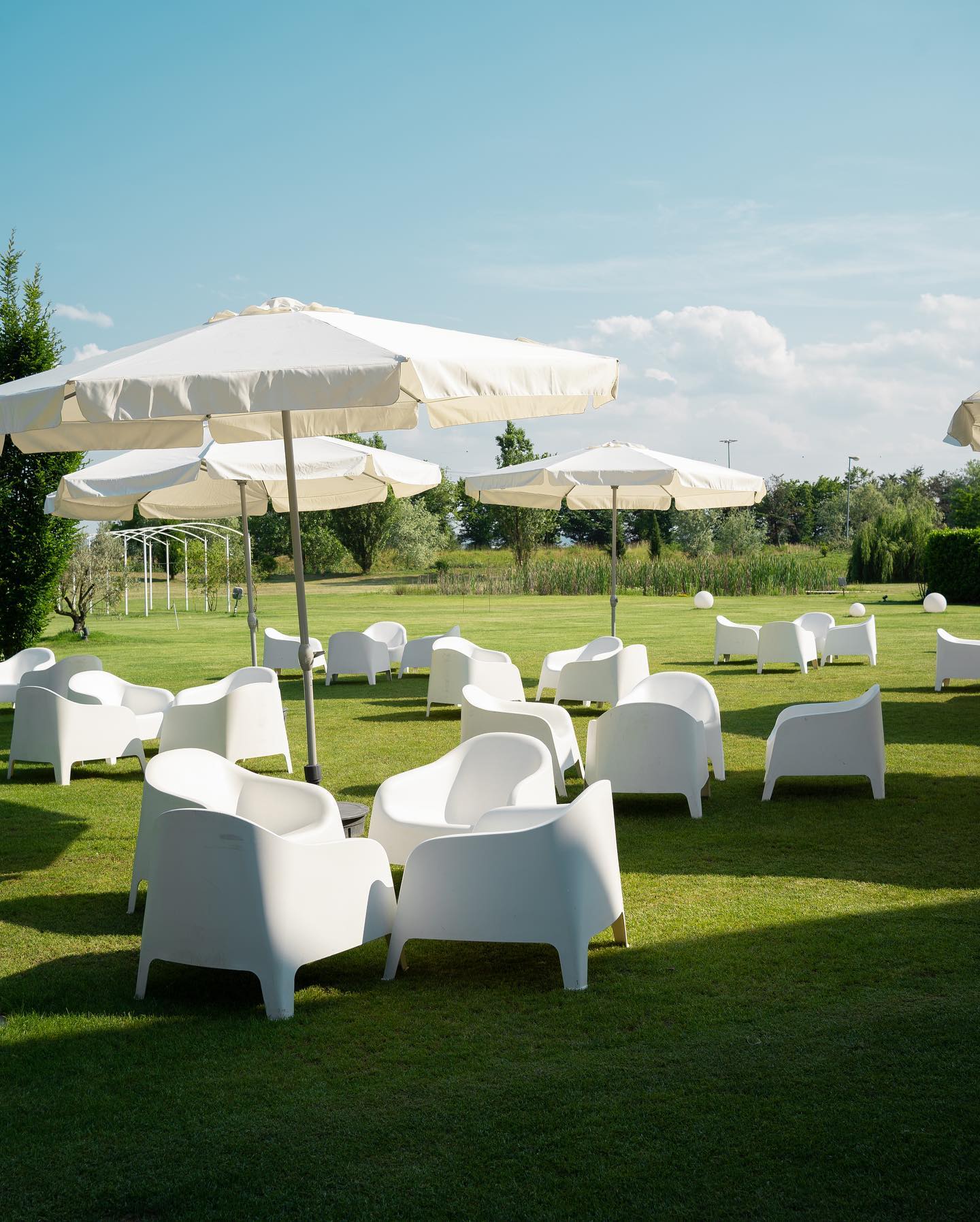 Giardino esterno dell'Hotel Rondissone con ombrelloni bianchi e poltrone da esterno